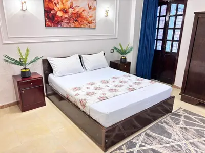 a bed in a room with two tables and a painting at Full Moon House in Luxor