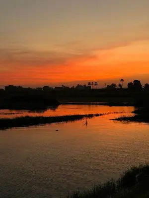 a sunset over a body of water with the sky at Al Salam Camp in Luxor