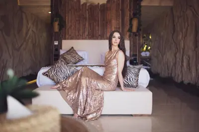 a woman in a gold dress sitting on a couch at Caves Beach Resort Adults Only in Hurghada