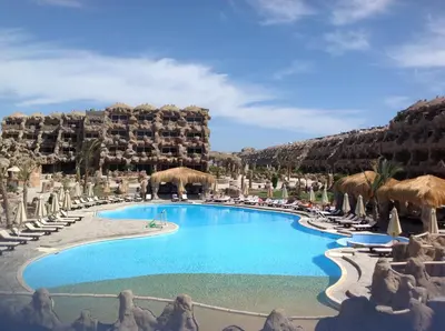 a pool at a resort with chairs and a hotel at Caves Beach Resort Adults Only in Hurghada