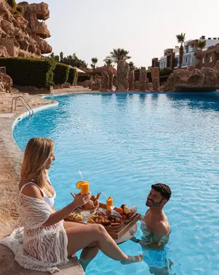 a man and a woman sitting in the swimming pool at Caves Beach Resort Adults Only in Hurghada