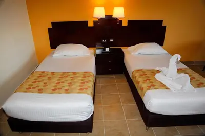 two beds in a hotel room with towels on them at Coral Sun Beach in Safaga