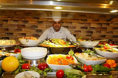 a chef in a kitchen with many plates of food at Coral Sun Beach in Safaga