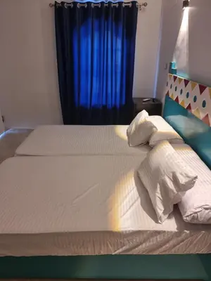 a bed with two white pillows and a blue curtain at Baba Dool in Aswan