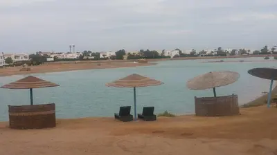 a group of umbrellas and chairs in front of a body of water at Twin Lagoon Apartment at White Villas El Gouna in Hurghada