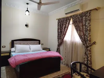 a bedroom with a bed with a pink blanket and a window at Luxor Star Apartments in Luxor