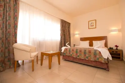 a bedroom with a bed and a chair and a window at Hapi Hotel in Aswan