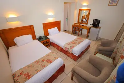 a hotel room with two beds and a chair at Hapi Hotel in Aswan