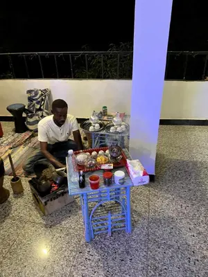 a man sitting next to a table with food on it at The Mango Guest House in Aswan
