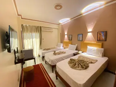 a hotel room with two beds and a television at Shady Hotel Luxor in Luxor