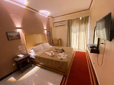 a small bedroom with a bed and a television at Shady Hotel Luxor in Luxor