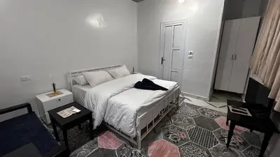 a white bedroom with a bed and a table at Luxor palace Apartments in Luxor