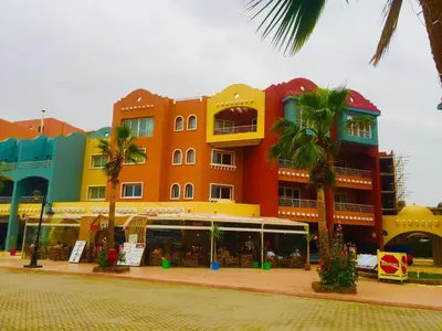 a colorful building with palm trees in front of it at Angie House Embassy area with wi fi in Hurghada