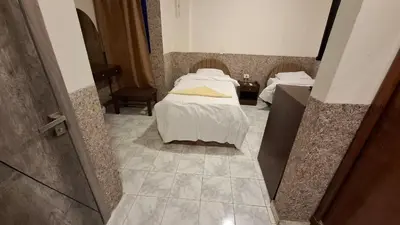 a bedroom with two beds and a tiled floor at Canary Hotel in Hurghada
