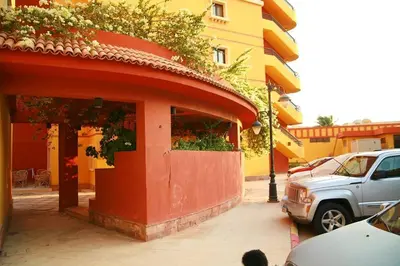 a red building with a car parked in front of it at Esplanada Beach Apartment, no single men in Hurghada