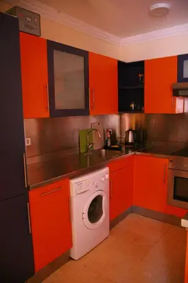 a kitchen with orange cabinets and a washing machine at Esplanada Beach Apartment, no single men in Hurghada