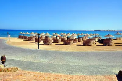 a beach with umbrellas and chairs and the ocean at Palm Beach Piazza Apart hotel Sahl Hasheesh in Hurghada