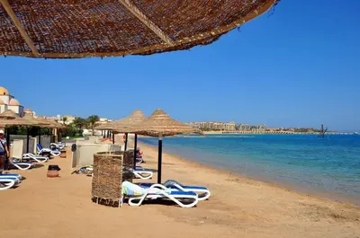a group of chairs and umbrellas on a beach at Palm Beach Piazza Apart hotel Sahl Hasheesh in Hurghada