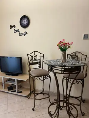 a table with chairs and a vase of flowers on it at Palm Beach Piazza Apart hotel Sahl Hasheesh in Hurghada
