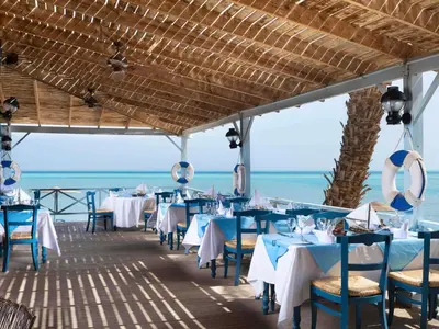 a restaurant with tables and chairs with the ocean in the background at Movenpick Resort & Spa El Gouna in Hurghada