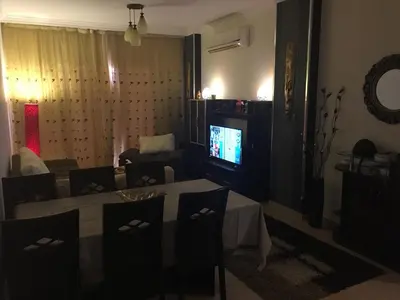 a living room with a table and a television at Pool View Apartment at British Resort - Unit 02 in Hurghada