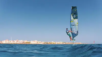 a person is windsurfing in the ocean on the water at Robinson Soma Bay in Hurghada