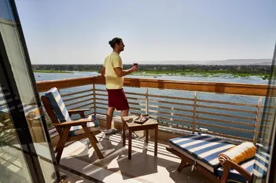 a man standing on a balcony looking out at the water at Sonesta St. George Hotel - Convention Center in Luxor