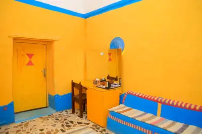 a yellow room with a desk and a yellow door at Nubian Palace Eco Lodge - A Nubian Home Since 1959 in Aswan