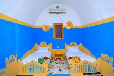 two beds in a room with blue walls at Nubian Palace Eco Lodge - A Nubian Home Since 1959 in Aswan