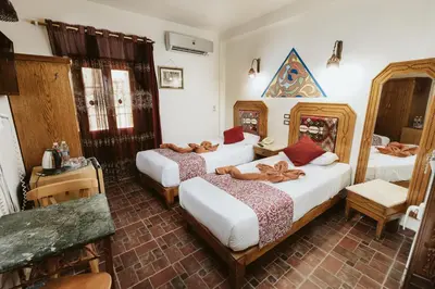 a bedroom with two beds and a table at Nefertiti Hotel Luxor in Luxor