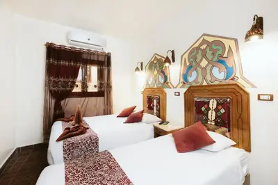 a room with two beds and a mirror on the wall at Nefertiti Hotel Luxor in Luxor