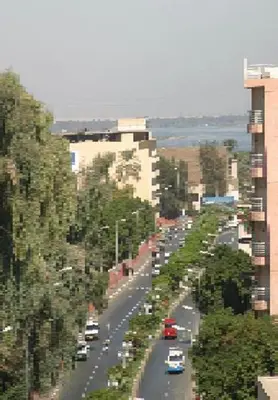 a street with cars driving down a road with trees at St.Joseph Hotel in Luxor