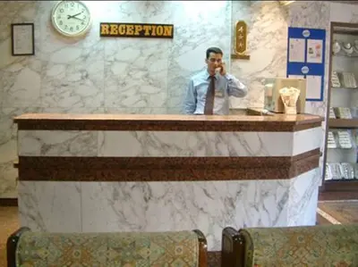 a man standing behind a counter talking on a cell phone at St.Joseph Hotel in Luxor