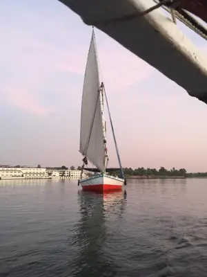 a small sailboat on the water near a bridge at Gold Ibis Hotel in Luxor