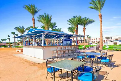 a restaurant with tables and chairs and palm trees at Pickalbatros The Palace Port Ghalib in Port Ghalib