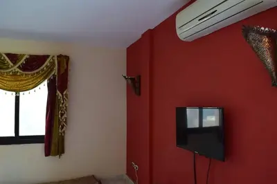 a room with a red wall with a tv and a window at chalet Stella de Mari in Makadi Bey in Hurghada