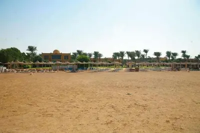 a beach with chairs and umbrellas and a building at chalet Stella de Mari in Makadi Bey in Hurghada