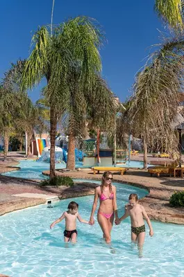 a woman and two children in a swimming pool at Three Corners Sea Beach Resort in Coraya Bay