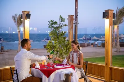 a man and a woman sitting at a table with a table cloth at Three Corners Sea Beach Resort in Coraya Bay