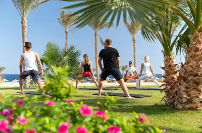 a group of people doing yoga on the grass near the beach at Three Corners Sea Beach Resort in Coraya Bay