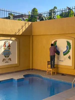 a man standing on a bench next to a pool at Jewel Howard Carter Hotel in Luxor