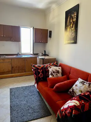 a living room with a red couch and a kitchen at Jewel Howard Carter Hotel in Luxor