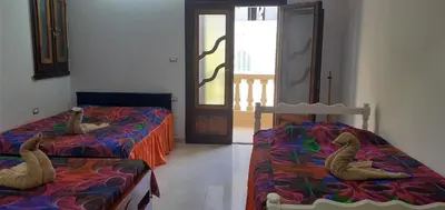 a room with two beds and a door to a hallway at Villamar Sea View rooms & apartments in Hurghada