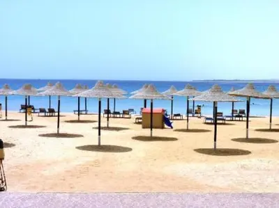 a group of umbrellas on a beach with the ocean at Apartment at Palm Beach Piazza in Hurghada