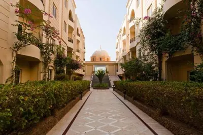a walkway between two buildings with a mosque in the distance at Apartment at Palm Beach Piazza in Hurghada