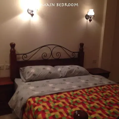 a bed with a wooden headboard with a colorful blanket on it at Apartment at Palm Beach Piazza in Hurghada