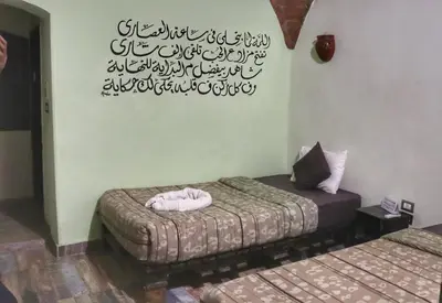 a room with two beds and a writing on the wall at Hadouta Masreya Nubian Guest House in Aswan