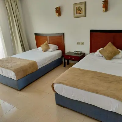 a hotel room with two beds and a table at Sharm El Naga Resort and Diving Center in Hurghada