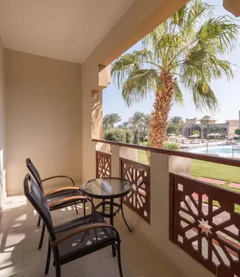 a balcony with a table and chairs and a palm tree at Serenity Alpha Beach - Ex Serenity Makadi Beach in Hurghada