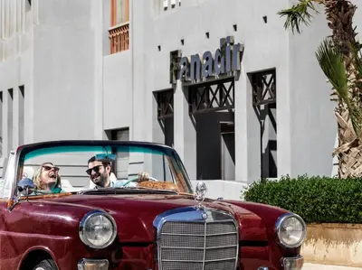 two people in a red car in front of a building at Fanadir Hotel El Gouna in Hurghada